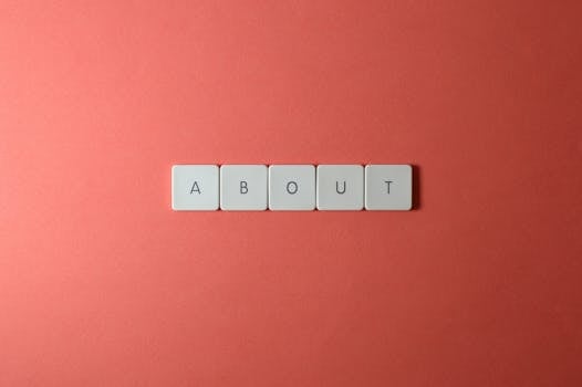 Close-up of keyboard buttons spelling 'ABOUT' against a red surface, minimalist style.